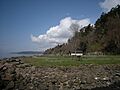 Picnic tables on a lawn surrounded by a steep rocky beach