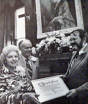 William Taupier gives Mary E Preiss a certificate of commendation for her work for Wistariahurst