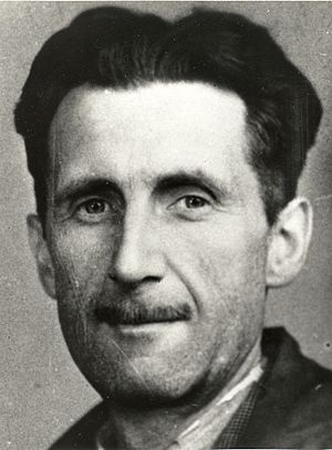 Photograph of the head and shoulders of a middle-aged man, with black hair and a slim mustache