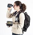  A Woman with a backpack holding a laser rangefinder, a handheld GPS and a Tablet computer. 