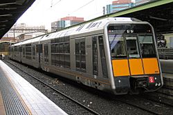 An outer-suburban Tangara in original livery with orange front.