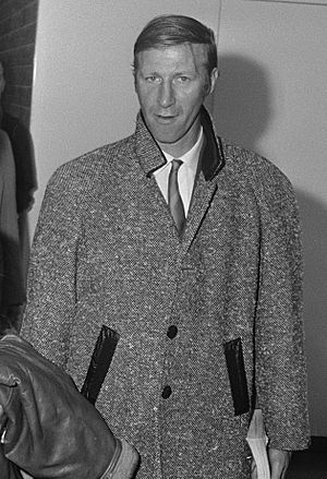 A black-and-white photo of Charlton in a long coat