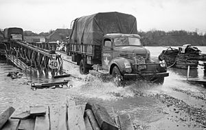 British supply trucks crossing a Bailey bridge over the Maas in full flood at Maeseyk in Holland, 25 November 1944. B12119