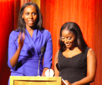 CNN Correspondent Nima Elbagir accepts the Peabody for CNN's coverage of the kidnapped Nigerian school girls. She is joined on stage by Isha Sesay.png