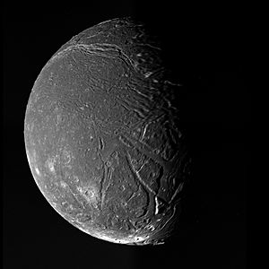 The dark face of Ariel, cut by valleys and marked by craters, appears half in sunlight and half in shadow