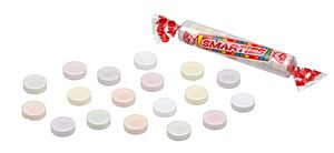 An image of Smarties tablet candies on a white background. On the right is a roll of candies consisting of 15 multicolored tablets in a clear film wrapper. The wrapper displays the Smarties Candy Company logo. On the left are a selection of loose Smarties candies.