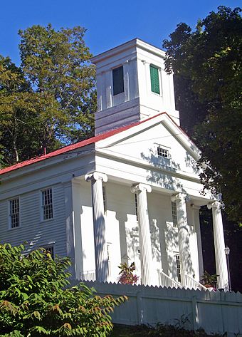 A white building with four columns in front and a red roof