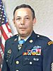 A colored photo of Littrell wearing his military dress uniform with ribbons and no hat. He is looking at the camera and an American flag is visible in the background.
