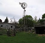 View of a wind wheel near two 19th century wooden structures at Riverdale Farm