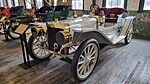 A white-colored, old-fashioned car with four seats and brass fittings