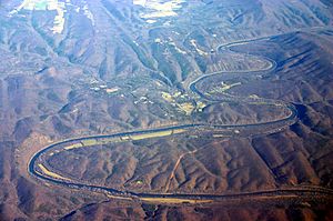 Oblique air photo of the meandering Potomac River at Little Orleans (center), facing north. The photo shows Allegany County, Maryland (left), Morgan County, West Virginia (right), Sideling Hill (right), and the Chesapeake and Ohio Canal.