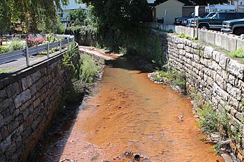 a small, orange-red stream flanked by high stone walls