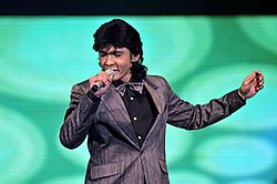 Jamal Abdillah singing onstage, wearing a black shirt and grey blazer and matching bowtie