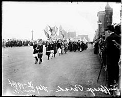 Black-and-white photo of people marching down a city street.