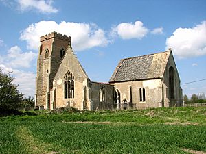 The ruins of a church from the southeast showing from the left a battlemented tower, the gable end of the roofless south transept, and the roofed chancel