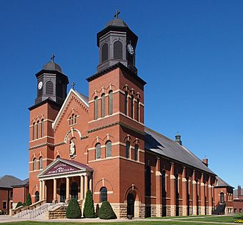 Large brick church on raised stone foundation with twin flanking belltowers