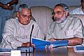 Modi and former Prime Minister Vajpayee looking at a blue-covered report