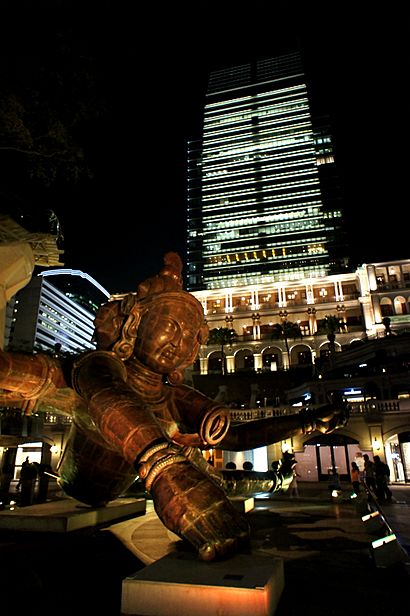 The sculpture lit up at night with a skyscraper behind it