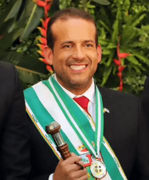 Headshot of Luis Fernando Camacho adorned in gubernatorial regalia and holding a baton.