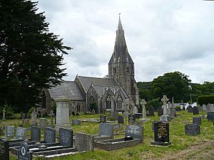 A medium-sized church with a tall stone steeple in a graveyard.
