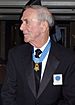a colored image of an elderly McNerney in a business suit wearing his Medal of Honor around his neck. He is facing to the left.