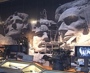 Photo of a display in the Exhibit Hall with blacksmith equipment on the right, a piece of honeycombed granite in the center and (f50a806c-155d-4519-3e8c-b63c3fcd8ceb).jpg