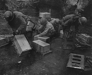SC 374765 - Infantrymen of the 94th Division, 3rd U.S. Army, strap cases of "K" rations to rackboards, to be carried up to the front line. 25 February, 1945. (52117540126)