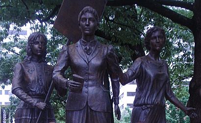 a bronze sculpture of three striding women
