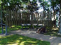 Wooden posts in a semicircle around information boards and a cannon