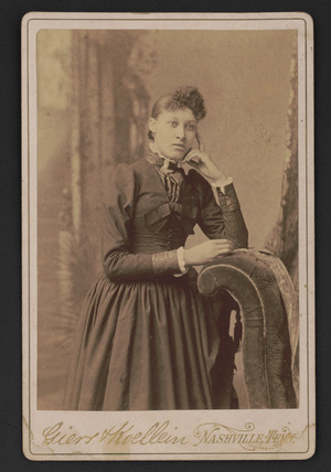 Portrait of journalist, Lillian Parker Thomas, standing before studio backdrop