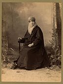 Turkish woman, full-length portrait, seated, facing front, holding parasol