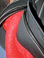 Detail of the zipper of a semi-dry wetsuit, showing one end of an open zipper and the neoprene flaps that cover it on the inside and outside of the suit to protect the zipper, improve comfort, and reduce leakage through the closed zip.