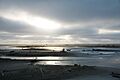 Sandy beach with sunbeams peeking through overcast sky