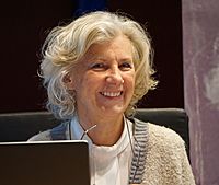 Photo of a gray-haired smiling woman wearing a white blouse and green sweater