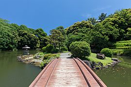Wooden footbridge in Shinjuku Gyoen National Garden, Tokyo, Japan, a sunny day with blue sky
