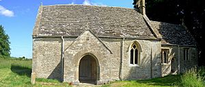A very small stone church seen from the south with a prominent doorway, and a smaller chancel towards the right