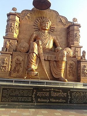 Large statue of a seated Vikramaditya, holding a sword