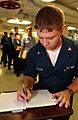 US Navy 040607-N-2788L-191 Machinist Mate 2nd Class Thomas Waller, from Lexington, Neb., writes a personal message in a book, which is going to be presented by USS Ronald Reagan's (CVN 76) Commanding Officer, Capt. James A. Sym