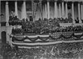 Photograph of crowd in front of Capitol building decorated with patriotic bunting