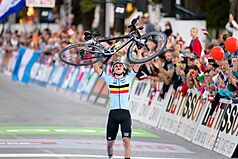 Remco Evenepoel holds his bicycle above his head after crossing the finish line