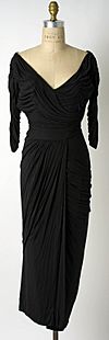A sleeved black dress held on a mannequin.
