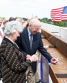 US Navy 090824-N-9876C-013 Retired Navy captain and former astronaut Jim Lovell and his wife, Marilyn Gerlach, sign the final roofing beam to be lifted into place during the topping off ceremony for the Captain James A. Lovell
