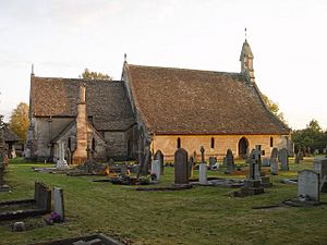 A church seen from the north with an extensive roof.  On the right is the nave with a bellcote at the west end; on the left is the chancel with the vestry.