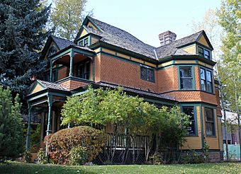 A large wooden house, yellow and orange with green trim and many projecting gables