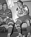 Richard, in full uniform except for his skates, sits on a locker room bench and stares at teammate Toe Blake beside him