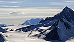A glacier, mountains of black gravel and snowcovered mountains.