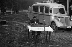 A man playing the Kantele in front of a broadcast van, 1930s