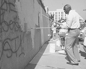 Nate Holden helping to paint over graffiti covered wall, 1989