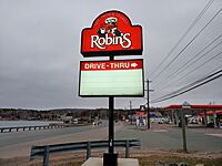 A business sign with an illustration of a cartoon bird and an arrow pointing to a drive-thru