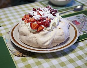 Pavlova garnished with cream and strawberries